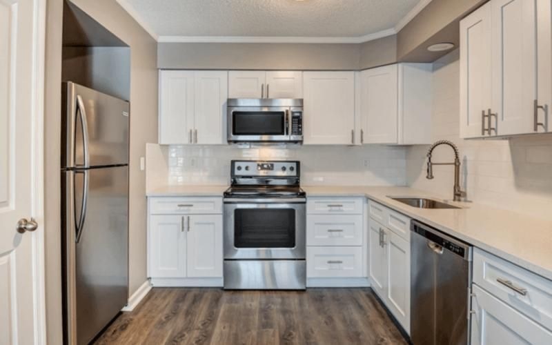 a kitchen with white cabinets and stainless steel applicances