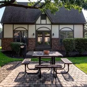 a building with a brick patio and picnic table in front