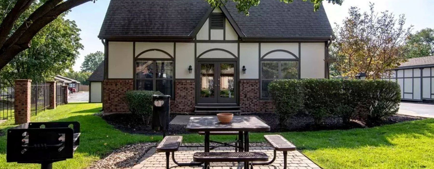 a building with a brick patio and picnic table in front
